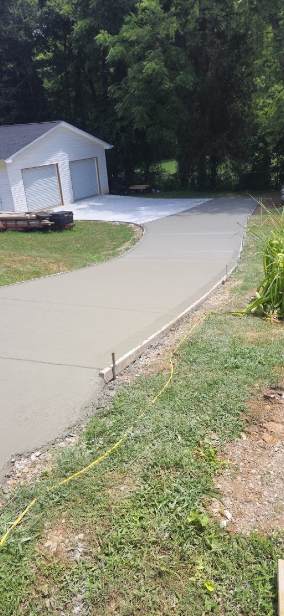 A curving concrete driveway running up to a garage, poured by T. Archer Concrete