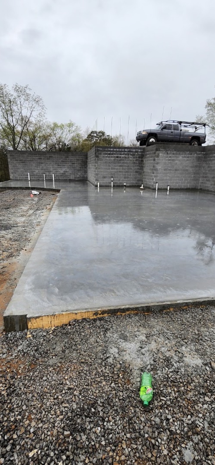 A block retaining wall behind a freshly poured concrete slab, by T. Archer Concrete