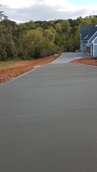 A fresh concrete driveway running down a wooded lot