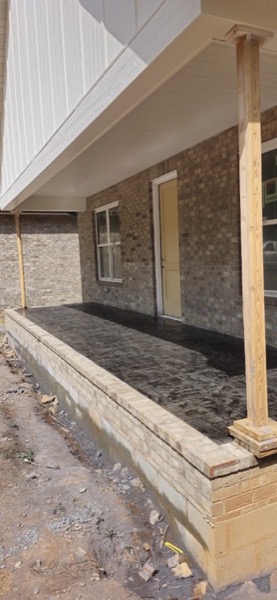 A stamped concrete porch beneath a covered entry