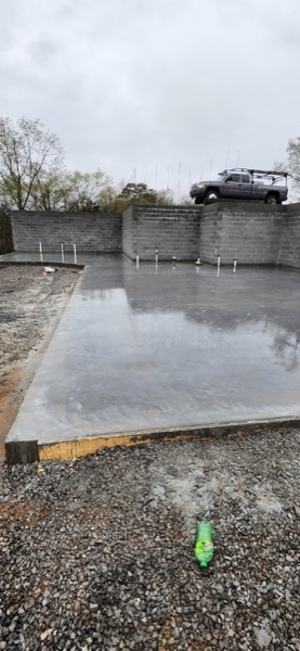 A concrete slab poured in front of a block retaining wall