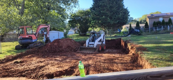 A skid steer moving dirt during site prep for a pour