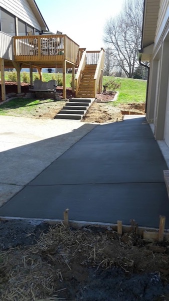 A concrete sidewalk running past a deck and steps