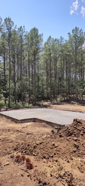 A concrete building pad poured on a wooded lot