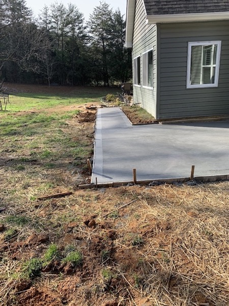 A concrete walkway running along the side of a house