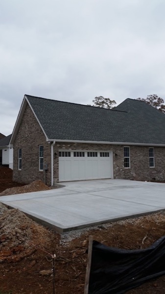 A concrete driveway finished at a brick home